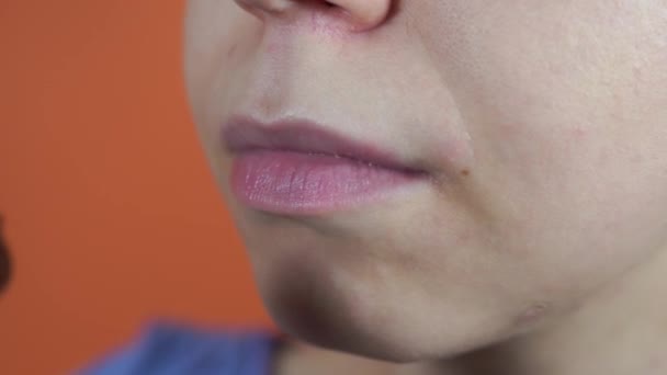 A portrait of the female body part on an orange background. A young woman is eating the breaded chicken nuggets. Close up of the mouth. — Stock Video