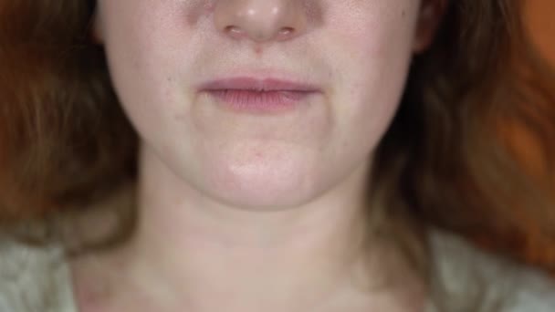 Een portret van het vrouwelijke lichaamsdeel op een oranje achtergrond. Een jonge vrouw eet de gepaneerde kipnuggets. Sluiten van de mond. — Stockvideo