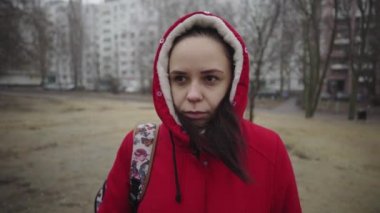 Kırmızı ceketli genç bir kadın bahçede soğuktan büzülüyor..