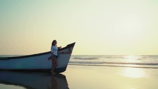 Uma Jovem Perto Barco Pelo Mar Contra Pôr Sol — Vídeo de Stock