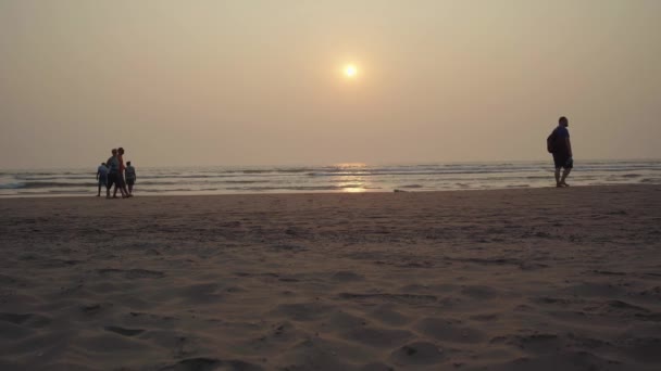 People walk on the beach at sunset. The concept of a lane along the sea or ocean. — Stock Video