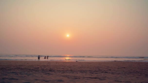 As pessoas caminham na praia ao pôr-do-sol. O conceito de uma faixa ao longo do mar ou do oceano . — Vídeo de Stock