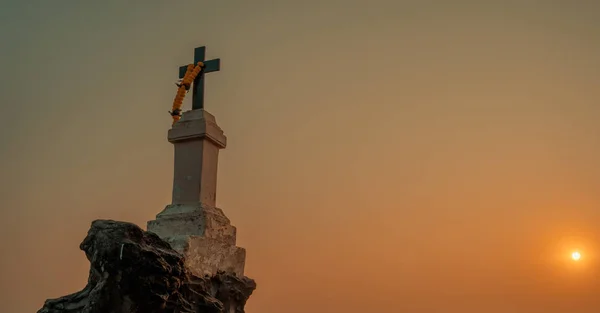 A cruz cristã com uma coroa floral contra o pôr do sol . — Fotografia de Stock