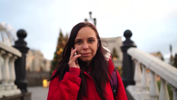 Una joven hermosa mujer está hablando en un teléfono móvil en un parque . — Vídeos de Stock