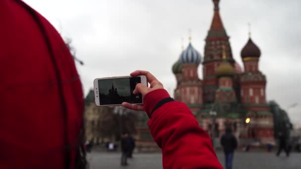 Una joven está tomando fotos del hito en un teléfono móvil. La niña está fotografiando al Kremlin de Moscú.. — Vídeo de stock