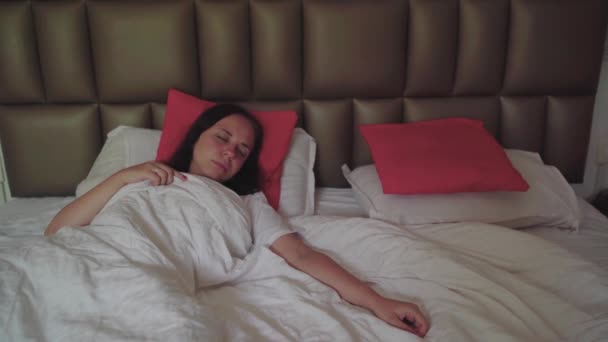 Uma bela jovem acorda em uma cama grande . — Vídeo de Stock