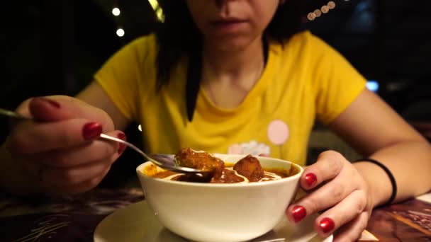 Una joven está comiendo un plato indio en un café tropical por la noche.. — Vídeos de Stock