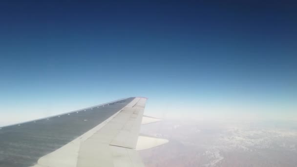 Wing of an airplane flying above the morning clouds. Airplane wing. And blue sky — Stock Video