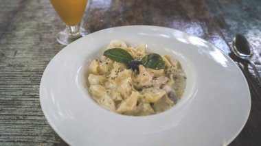 Büyük beyaz bir tabakta deniz mahsulleriyle birlikte bir tabak Carbonara ezmesi..