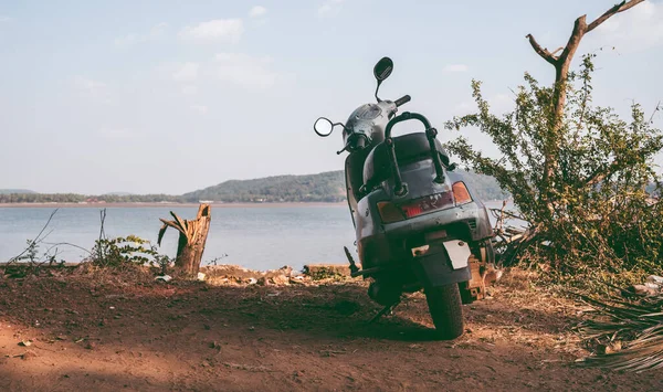 A scooter is parked on the coast of the sea or ocean.