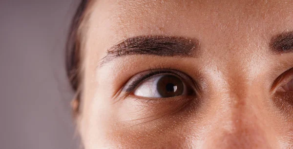 Um olho feminino após tatuagem permanente close-up. — Fotografia de Stock