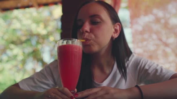 Une femme buvant un cocktail au café. Dame adulte sirotant des boissons de fruits frais à travers la paille tout en étant assis à la table dans le restaurant de la rue le jour ensoleillé — Video