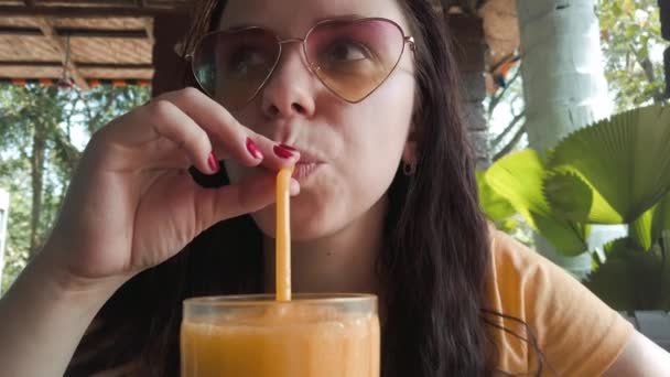 Donna che beve cocktail al bar. Donna adulta sorseggiando bevanda fresca di frutta attraverso la paglia mentre seduto a tavola nel ristorante di strada nella giornata di sole — Video Stock