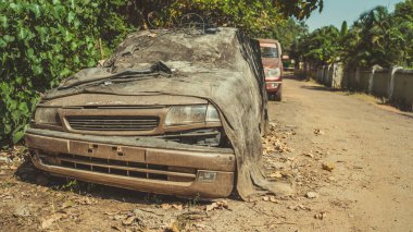 Şehir caddesinde kırık bir araba. Paslı hasarlı araba kirle kaplı. 