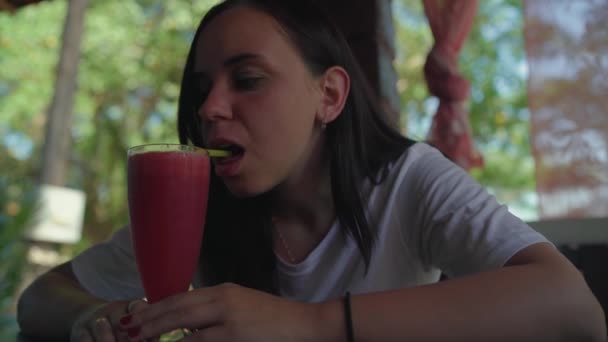 Donna che beve cocktail al bar. Donna adulta sorseggiando bevanda fresca di frutta attraverso la paglia mentre seduto a tavola nel ristorante di strada nella giornata di sole — Video Stock