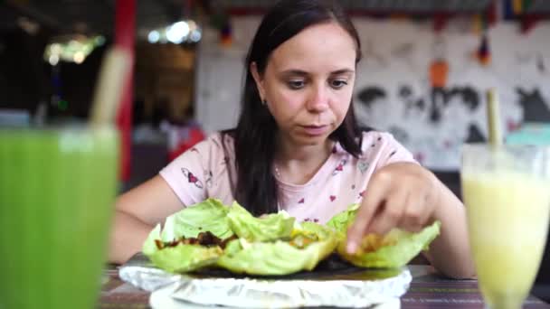 एक युवा महिला एक उष्णकटिबंधीय कैफे में एक बहुत गर्म भारतीय व्यंजन खा रही है . — स्टॉक वीडियो