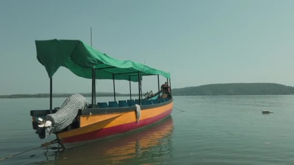 Denizde renkli bir turist teknesi. Güneşli bir günde bulutsuz mavi gökyüzüne karşı durgun deniz suyunda yüzen insanla parlak bir turist teknesi. — Stok video