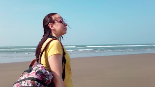 リュックサックを背負ったリラックスした女性が海岸を歩く — ストック動画