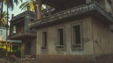 Karanlık camlı, ağaçlarla çevrili eski bir bina. Boş karanlık pencereleri, süslü çitleri ve aydınlık bir günde büyüyen yüksek ağaçları olan eski püskü, eski püskü bir ev.