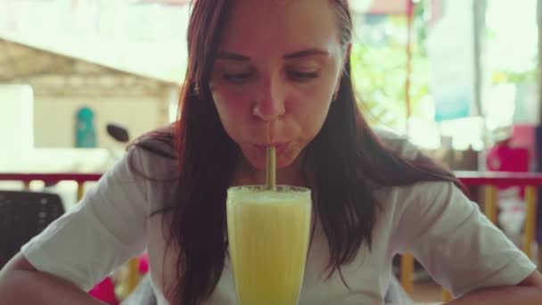 Woman drinking cocktail in cafe. Adult lady sipping fresh fruit beverage through straw while sitting at table in street restaurant on sunny day — Stock Video