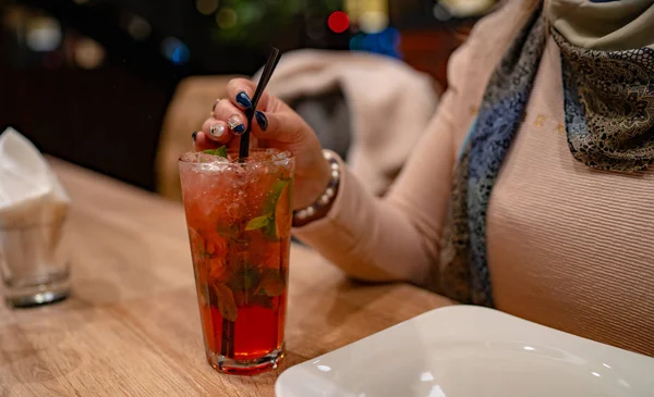 Женщина распивает алкогольный коктейль в кафе. Закрытие женщины, пьющей красный коктейль в кафе. Пьяные, люди и образ жизни - близко — стоковое фото