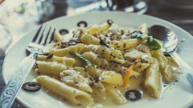 Kafe masasında nefis bir makarna. Lokantadaki masaya krema soslu lezzetli makarna ile yakın çekim tabağı.