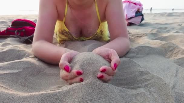 Frauenhände gewinnen Sand in ihrer Handfläche. Sand fällt ihr am Sandstrand aus den Händen. — Stockvideo