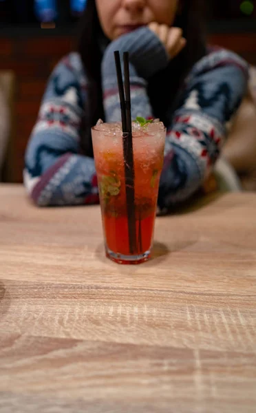 Eine Frau trinkt in einem Café einen alkoholischen Cocktail. Nahaufnahme einer Frau, die in einem Café einen roten Cocktail trinkt. Drinks, Menschen und Lifestylekonzept hautnah — Stockfoto