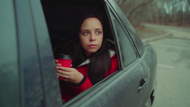 坐在车里的拿着一次性杯子的年轻女人 — 图库视频影像