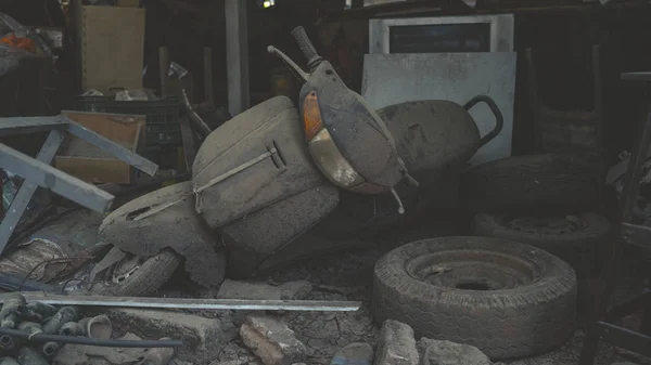 An old scooter is lying in a dump. A lot of old junk in the dust and dirt. — Stock Photo, Image