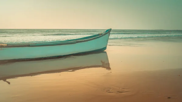 Пустая лодка на песчаном пляже в яркий день. Большая старая белая лодка на песчаном берегу, готовая в яркий день поплавать на пляже — стоковое фото