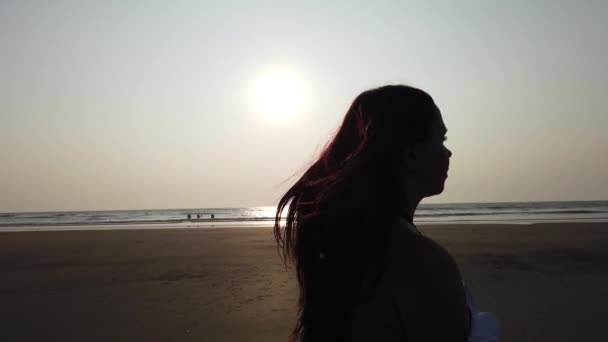 Joven mujer delgada hermosa en la playa de la puesta de sol. Mujer caminando en la playa bajo la luz del sol — Vídeos de Stock