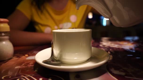 Frau gießt kochendes Wasser aus einer weißen Teekanne in einen weißen Becher, Nahaufnahme — Stockvideo