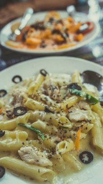 Kafe masasında nefis bir makarna. Lokantadaki masaya krema soslu lezzetli makarna ile yakın çekim tabağı.
