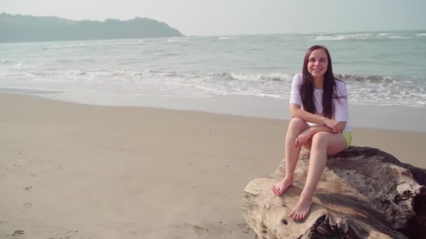 Stilig kvinna står på sandstrand nära havet. Kvinnlig turist ler glatt i solig dag på stranden. — Stockvideo