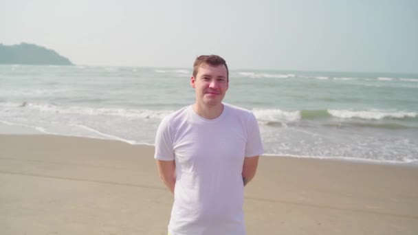 Мужчина одобрительно кивает головой о берег. Взрослый мужчина показывает жест согласия, стоя на песчаном пляже у моря или океана в яркий солнечный день. — стоковое видео