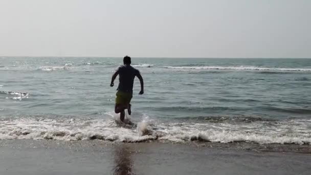 Männchen im Meer nahe der Küste. Attraktiver Mann im Meer, der Wasser spritzt und vor der Kamera posiert. Lächelnder Mann hat Spaß im Meerwasser. — Stockvideo