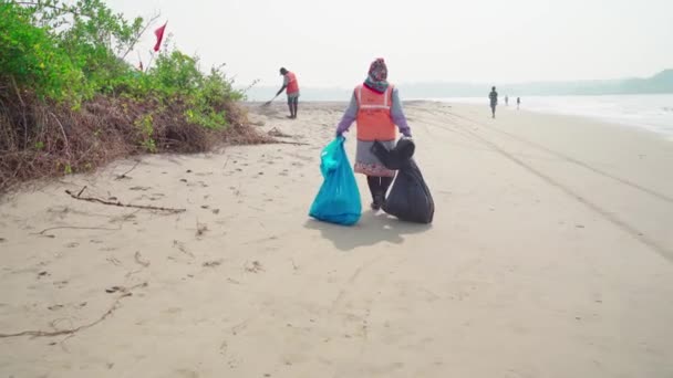 Morjim, India December 14, 2019: Cleaners establish order on seacoast from garbage. Workers make clean sandy beach for comfortable stay for tourists. — стокове відео