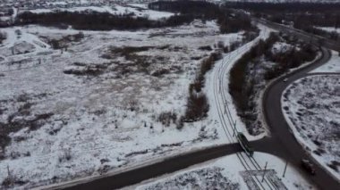 Kış mevsiminde kırsalda modern tramvay yolculuğu. Çağdaş tramvay yolculuğunun tepesinden bir görüntü. Kış günü trafik vardı. Kışın yolda giden arabalar, karla kaplı ağaçlar gökyüzü manzaralı..