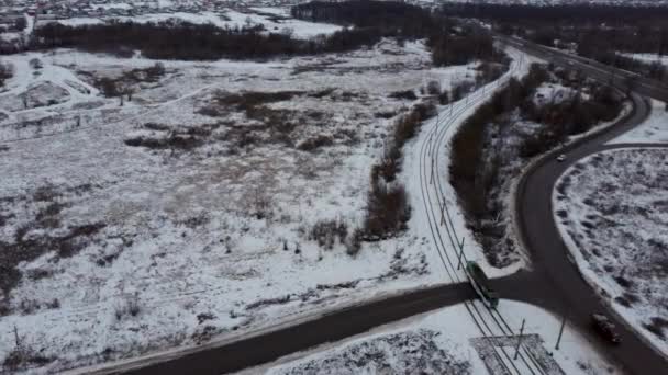 Moderne Straßenbahn fahren in der Wintersaison auf dem Land. Blick von oben auf das moderne Straßenbahnfahren. Verkehr an einem Wintertag. Autos auf Straßen im Winter mit schneebedeckten Bäumen Luftaufnahme. — Stockvideo