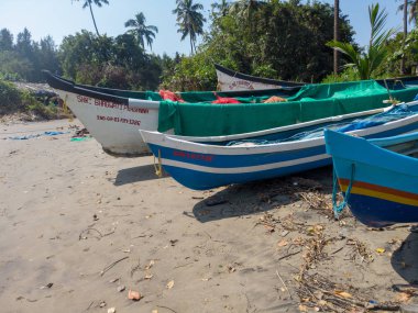 Morjim, India December 14, 2019: Empty boat on sandy beach in bright day. Large old white boat on sandy seaside ready to sail in bright day on beach