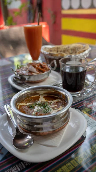 Närbild av exotiska rätter i gatucaféet. Indisk varm maträtt med kryddiga kryddor på bordet i tropiskt café. — Stockfoto
