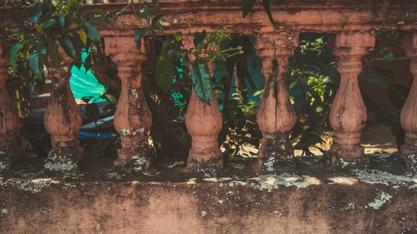 Primer plano de la vieja cerca rota. Interesante estructura arquitectónica con pintura pelada. ramas de árboles verdes envueltos alrededor de barandilla . —  Fotos de Stock