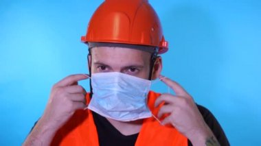 Sağlık maskeli ve tulumlu erkek inşaat işçisi.