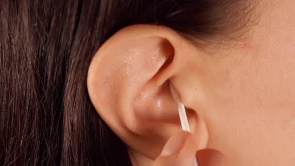 Close-up van vrouwenoor met wattenstaafje. Vrouw reinigt haar oor. Begrip lichaamsverzorging. — Stockvideo