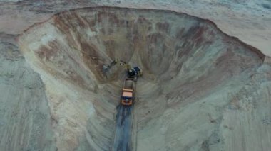 Kazıcı ve çöp kamyonu. Bir kamyona kum yükleme görüntüsü. Ağır bir makine, kazıcı ve kamyon kum ocağında çalışıyor..