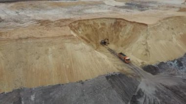 Kazıcı ve çöp kamyonu. Bir kamyona kum yükleme görüntüsü. Ağır bir makine, kazıcı ve kamyon kum ocağında çalışıyor..