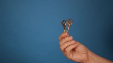 Farklı anahtarlarla yakın plan. Mavi arka planda iki anahtar tutan kadınlar..