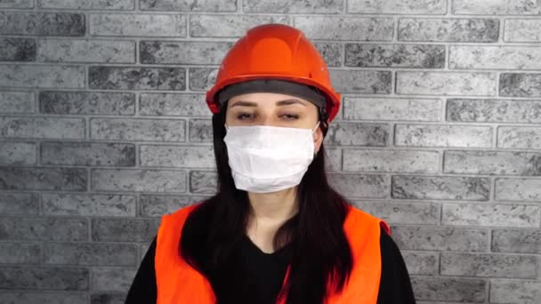 Ritratto di giovane donna in maschera medica sul viso su sfondo di muro di mattoni grigi. La femmina adulta si copriva il viso con una maschera per proteggersi dalle malattie. Concetto di epidemia di coronavirus o — Video Stock