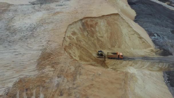 Excavator loading soil onto hauler Truck. Aerial view of loading sand into a truck. A heavy machinery - excavator and truck are working in the sand quarry. — Stock Video